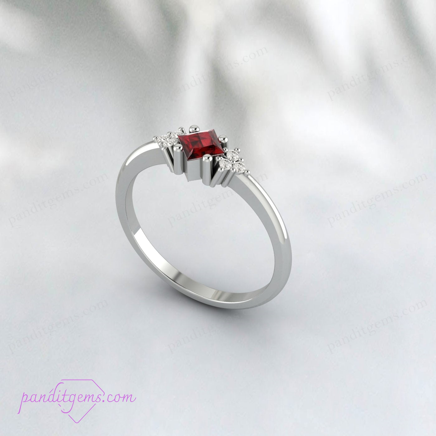 Close-up of a red garnet wedding ring with a sterling silver band and diamond accents.