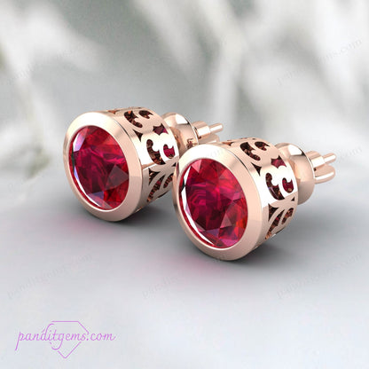 Bezel set ruby earrings in sterling silver, showcasing a brilliant-cut round ruby.