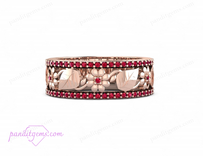 This image shows a close-up of a beautifully crafted rose gold wedding band with intricate leaf designs and a ruby centerpiece.