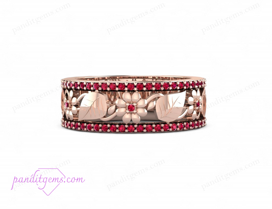 This image shows a close-up of a beautifully crafted rose gold wedding band with intricate leaf designs and a ruby centerpiece.